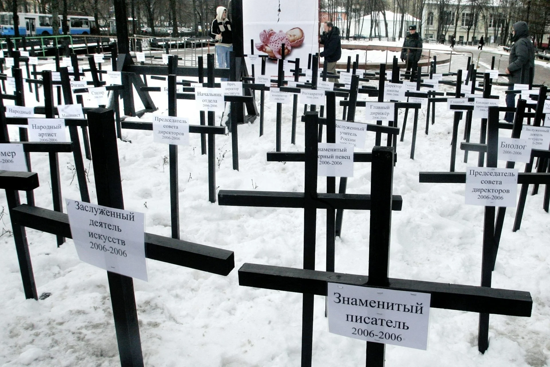 Rows of simple wooden crosses stand in snow.