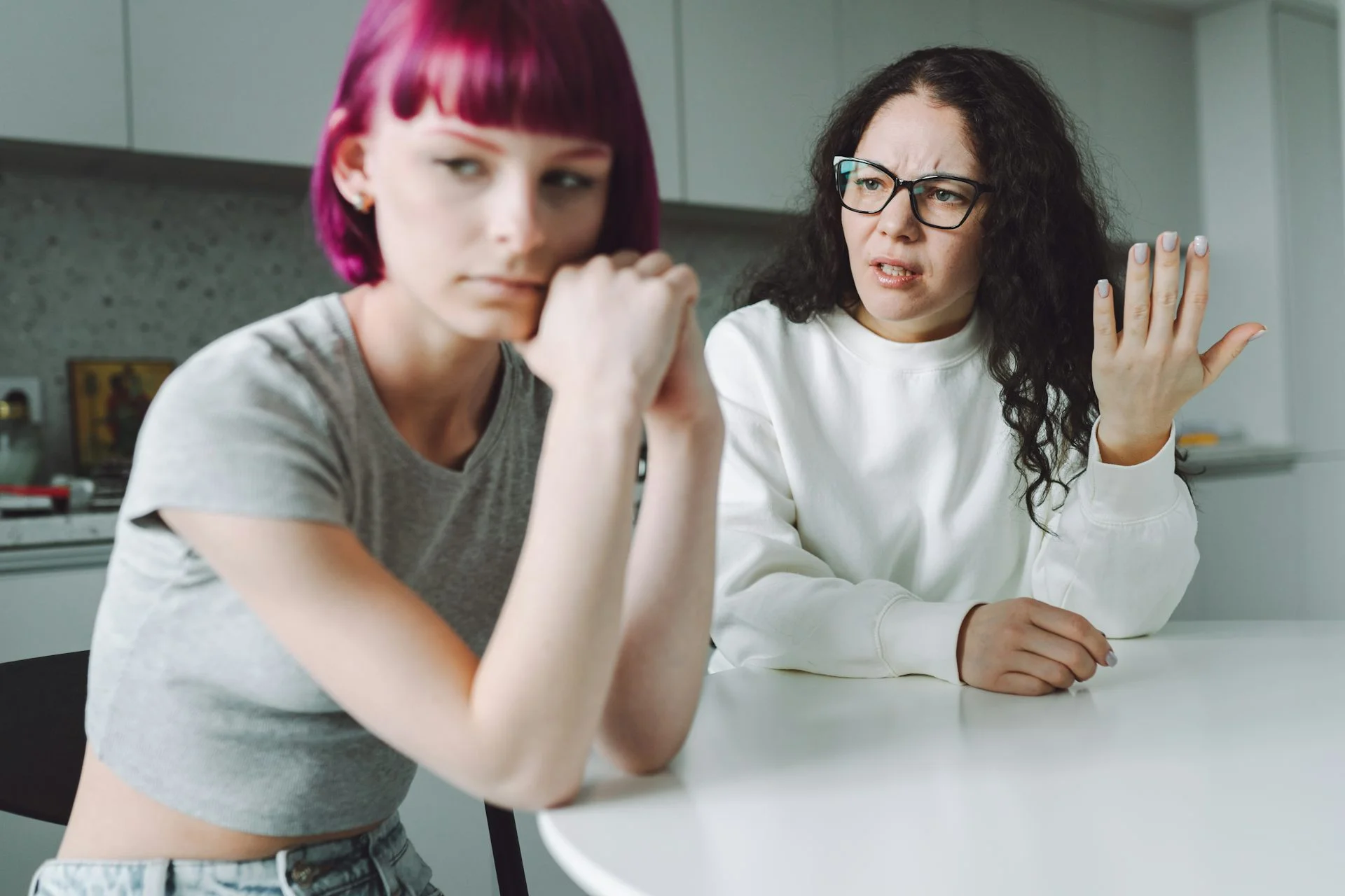 Single working mother and her teenage daughter talk with much emotion in the kitchen.