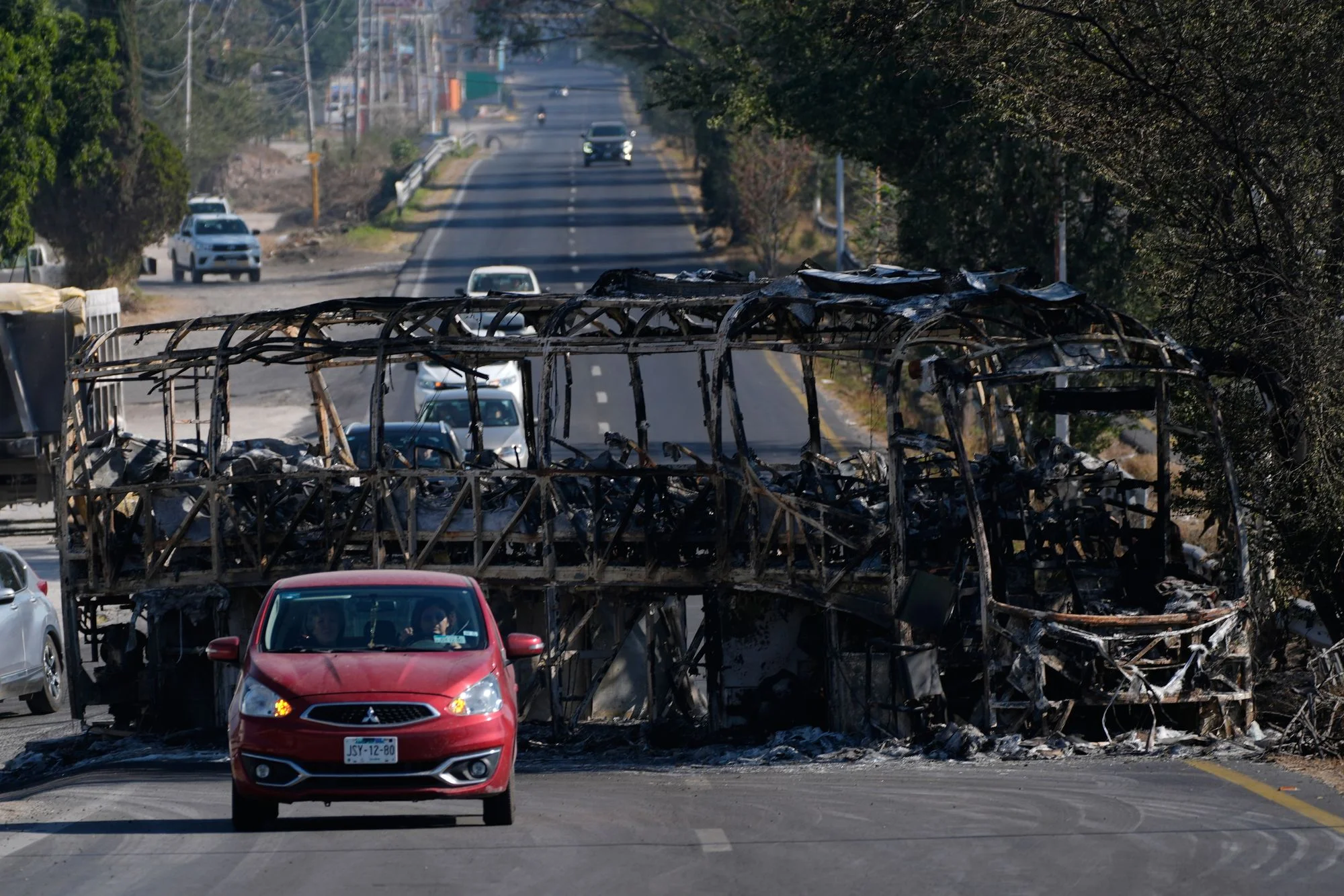 Vehicles drive past a charred bus the day after the Mexican army killed Jalisco New Generation Cartel leader Nemesio Oseguera Cervantes, known as El Mencho