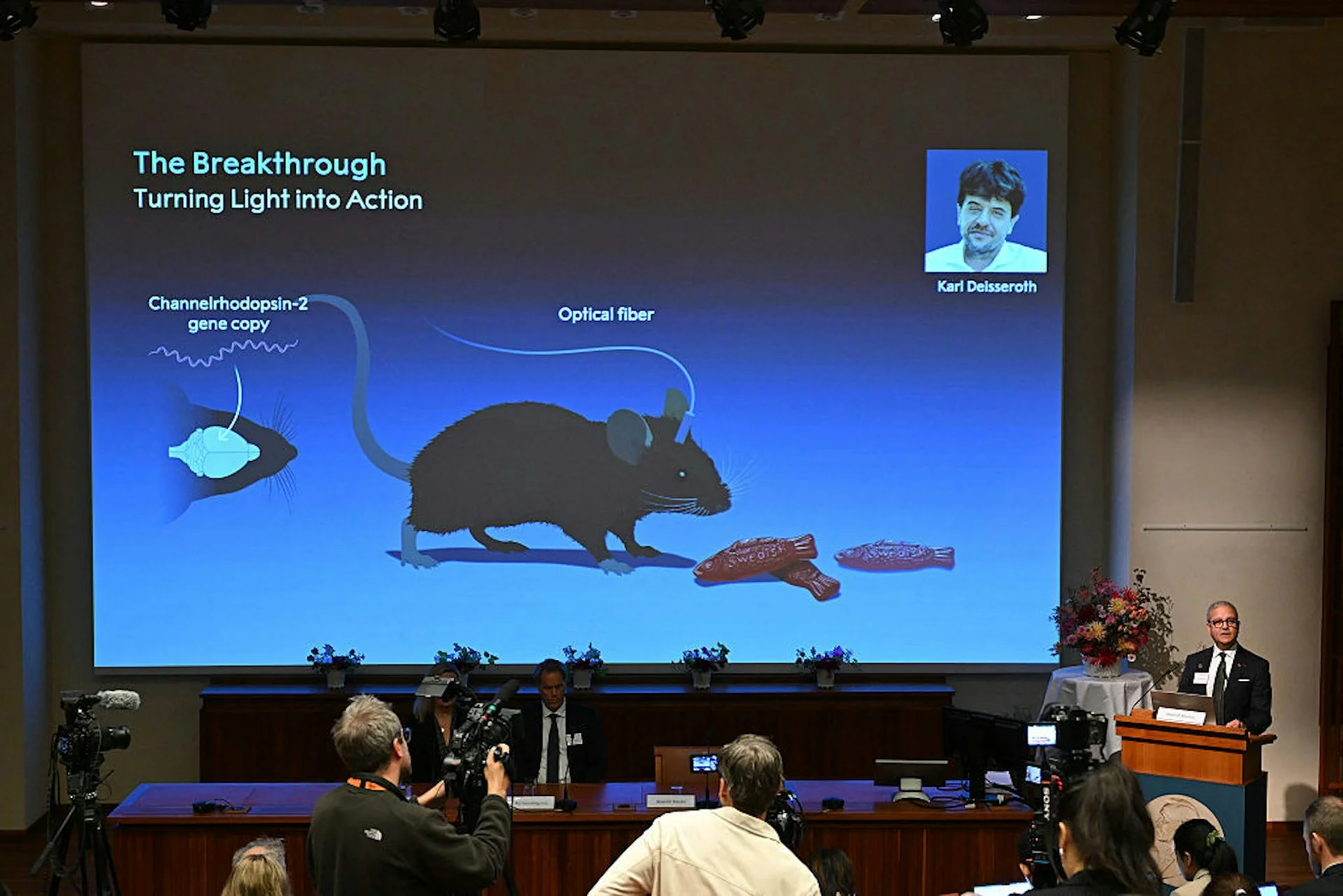 Presentation screen at Nobel Prize announcement, showing a diagram of a mouse with an optical fiber attached to its head